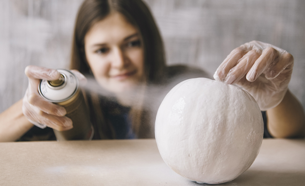 A person spray painting a pumpkin.