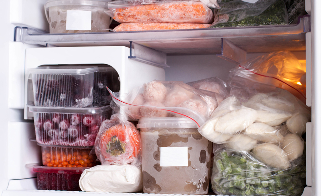 The inside of a freezer compartment with stacked frozen food. 