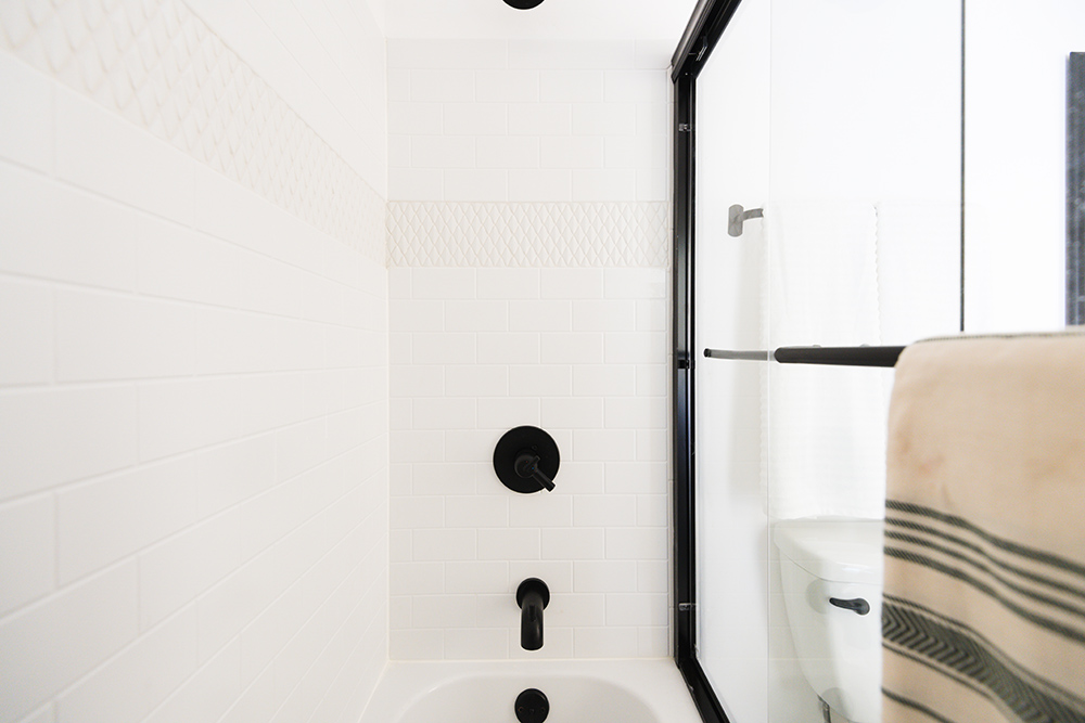 A white shower surround with tile detail.