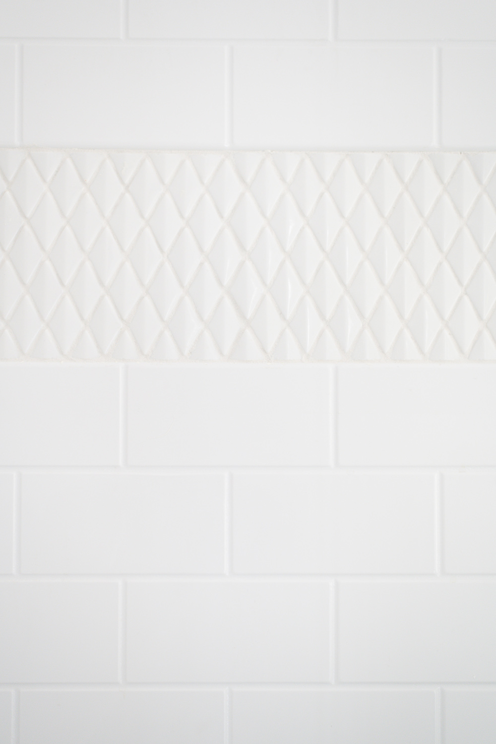 A white shower surround with white tile.