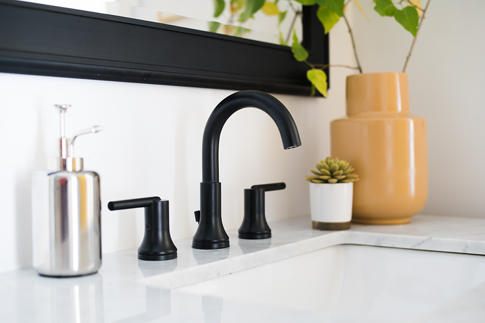 A matte black two handle bathroom faucet installed on a vanity.