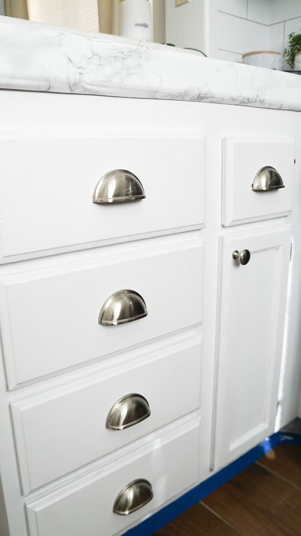 White lower kitchen cabinets with updated cabinet cup pulls.