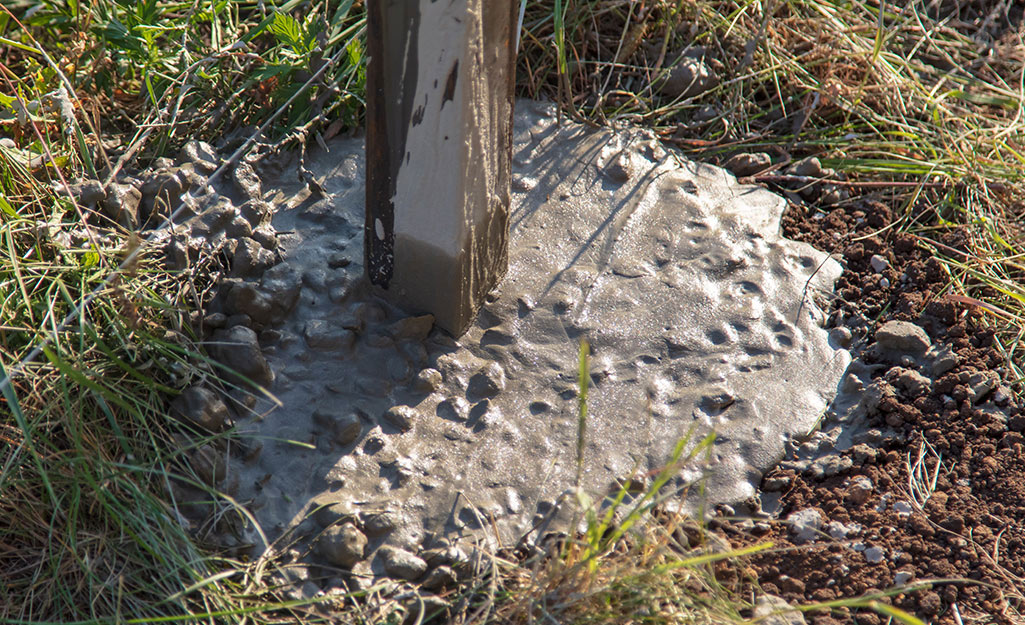 A picture of the concrete footing of a fence post.