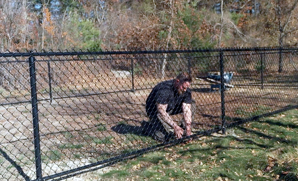 A person repairing a metal fence.