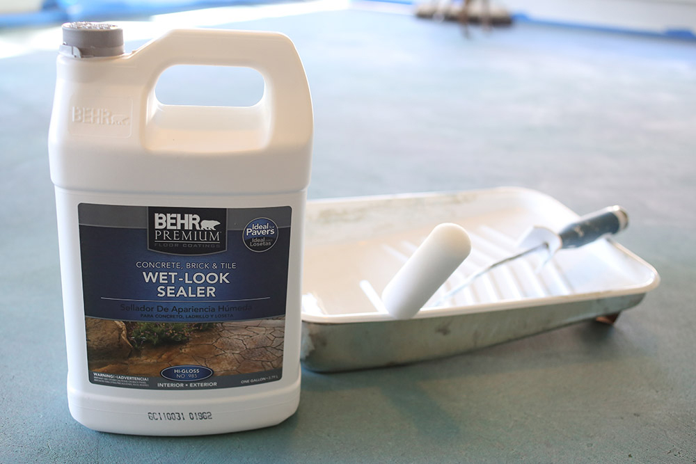 A bottle of Behr premium wet-look sealer, a paint tray, and roller. A bottle of Behr premium wet-look sealer, a paint tray, and roller.