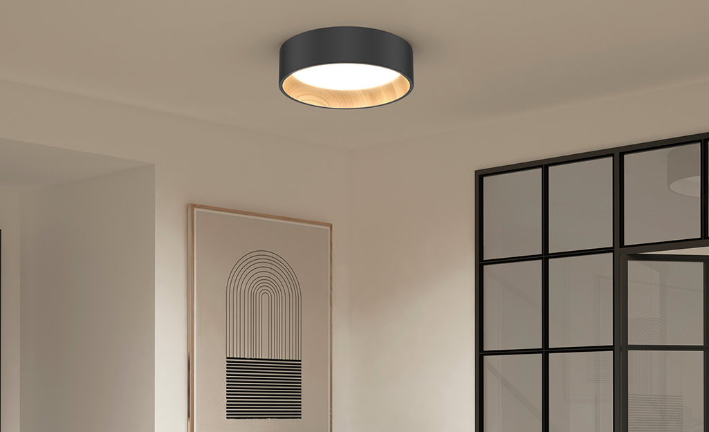 A modern style flush mount ceiling light in black and brass.