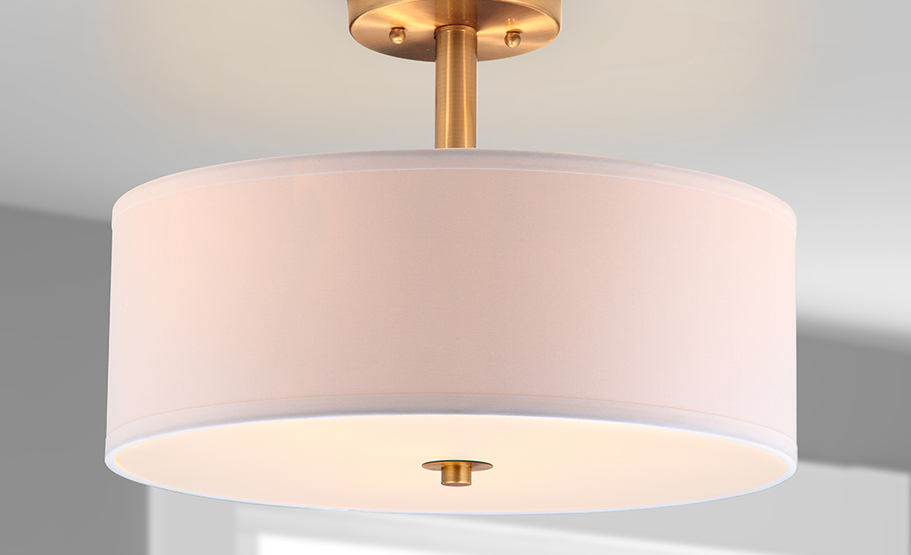 A pink fabric and brass semi-flush mount light.