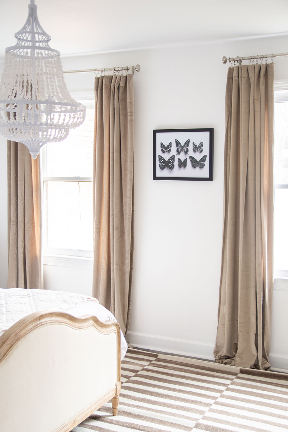 A bedroom scene featuring a modern light fixture overhead, neutral colored curtains and wall art. A bedroom scene featuring a modern light fixture overhead, neutral colored curtains and wall art.
