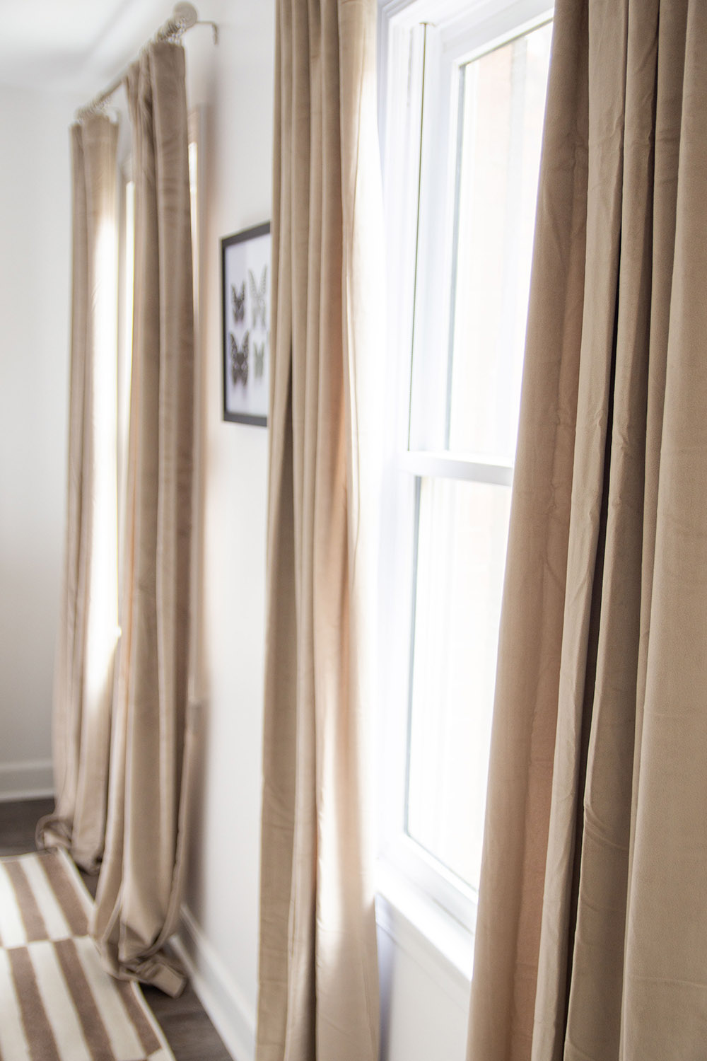 A white wall with neutral colored curtains and art. A white wall with neutral colored curtains and art.