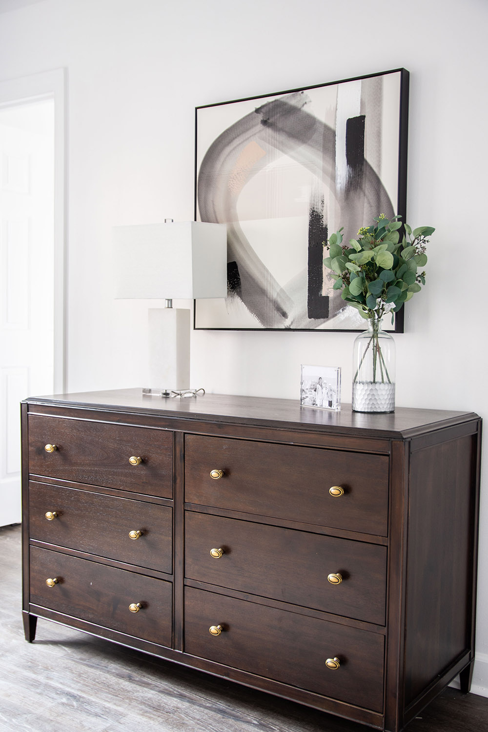 A bedroom wall featuring a wooden dresser and other decor items. A bedroom wall featuring a wooden dresser and other decor items.