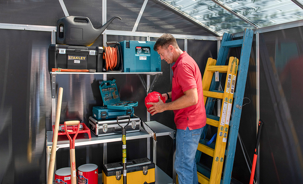 A person inside a shed with tools on a shelf.