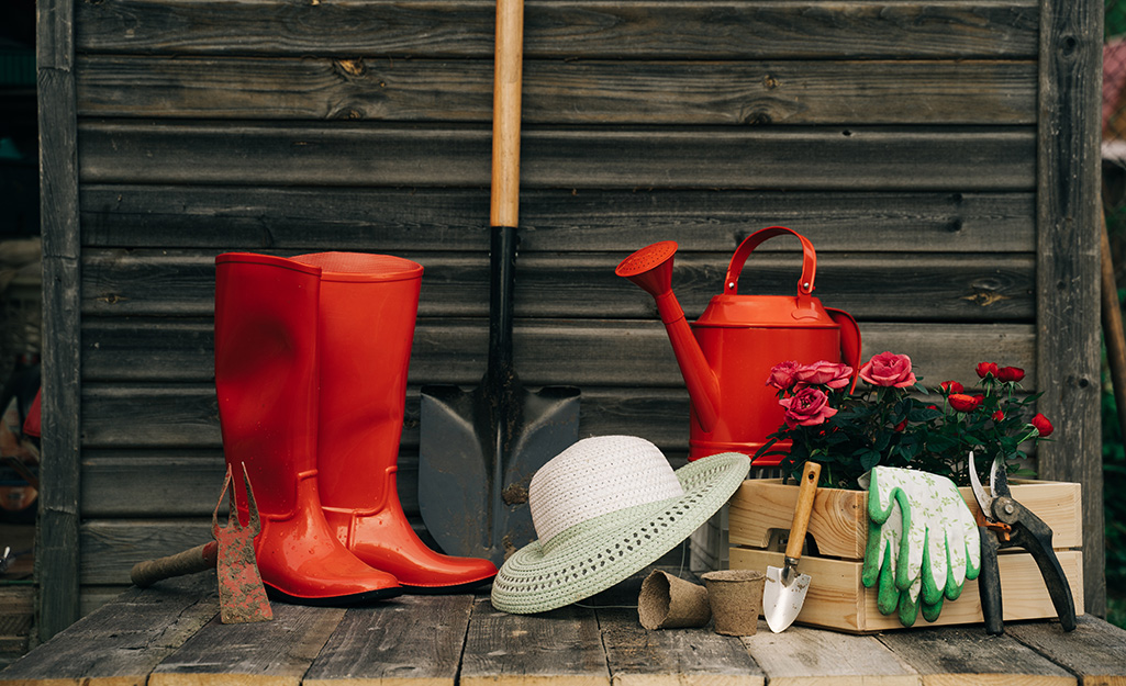A pair of gardening gloves, boots, a hat and other gardening supplies in a box.
