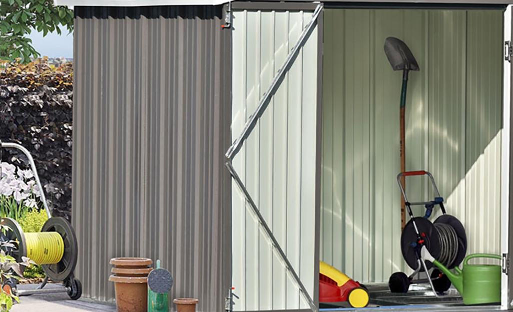 A portable hose wheel and shovel inside a shed.