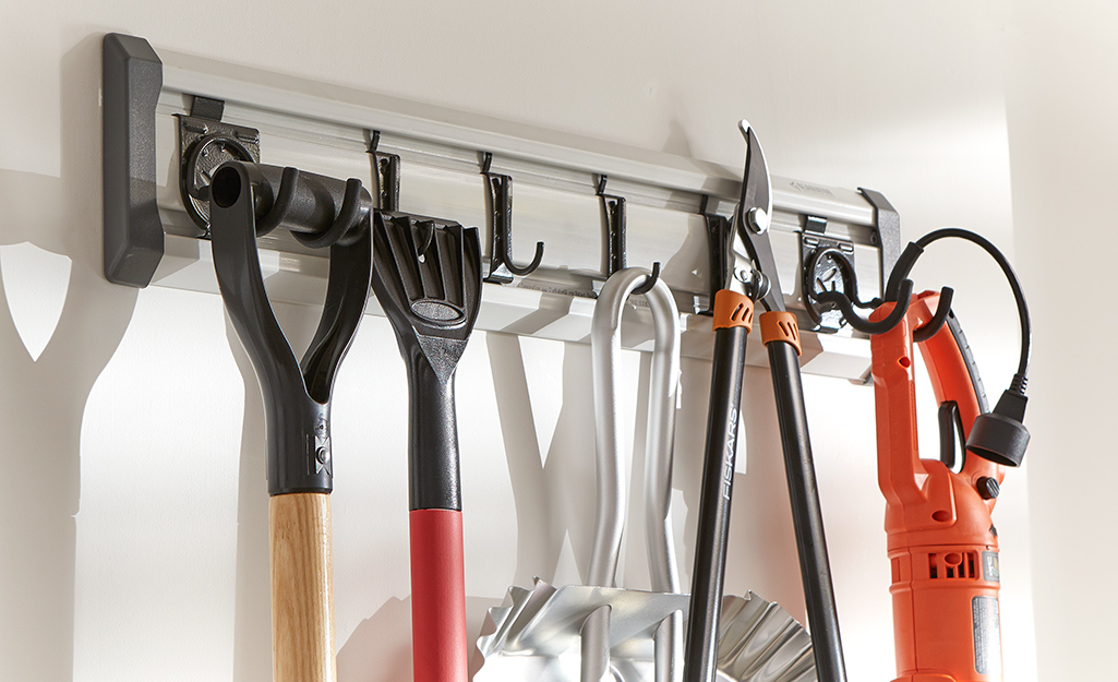 Garden tools hang from hooks on a wall.