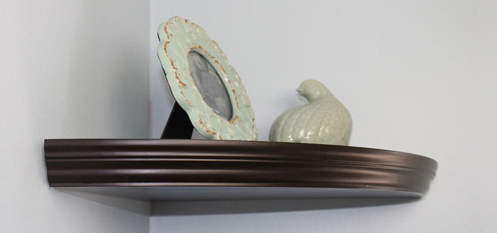 A brown wood corner shelf containing a small statue and a photo frame. A brown wood corner shelf containing a small statue and a photo frame.