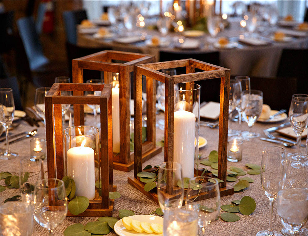 DIY wooden lanterns filled with candles sit on top of a table.