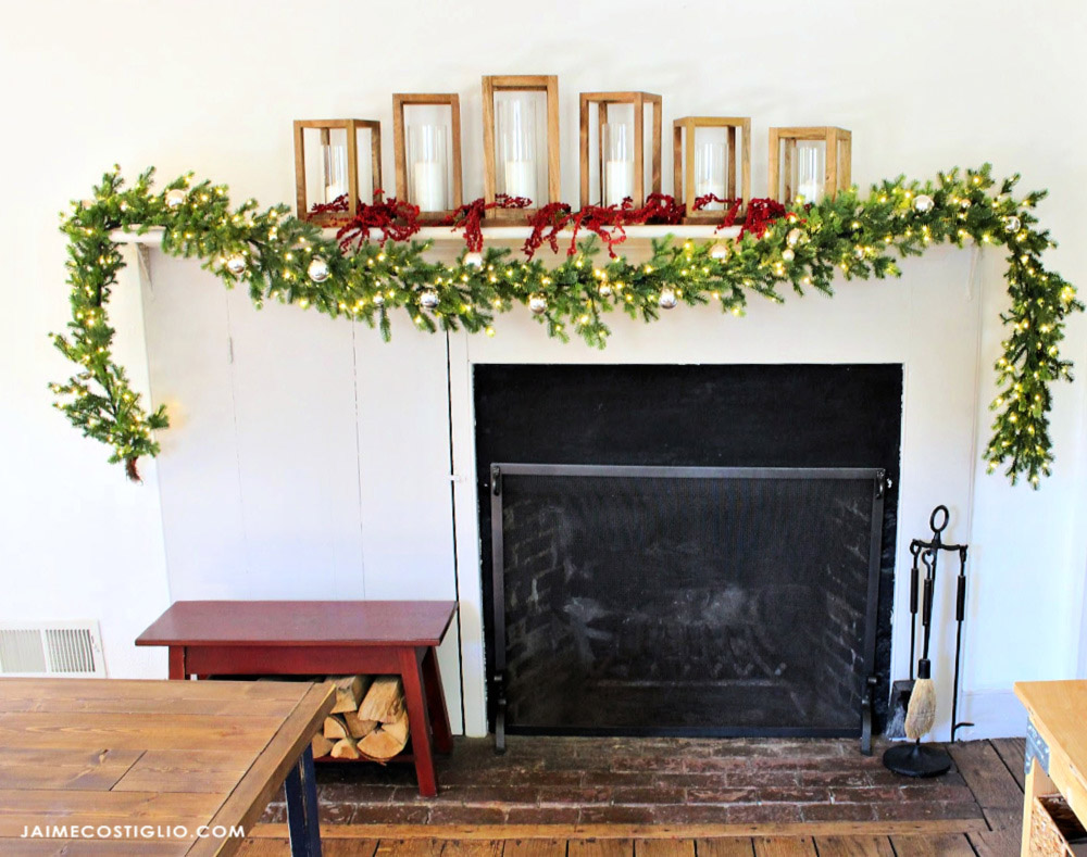 A mantel decorated with holiday garland and candles. 