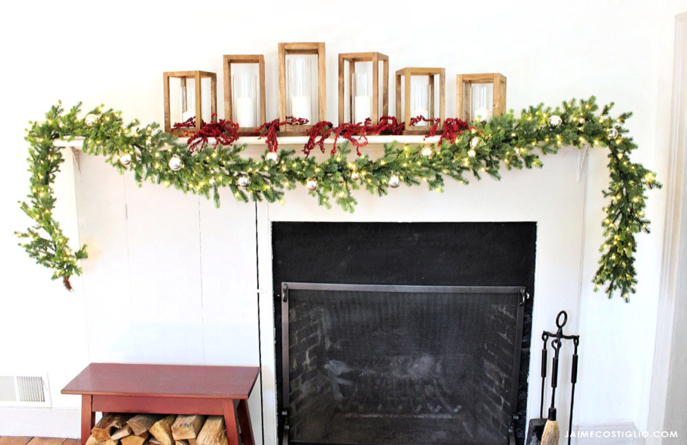 A mantel decorated with holiday garland and candles. 
