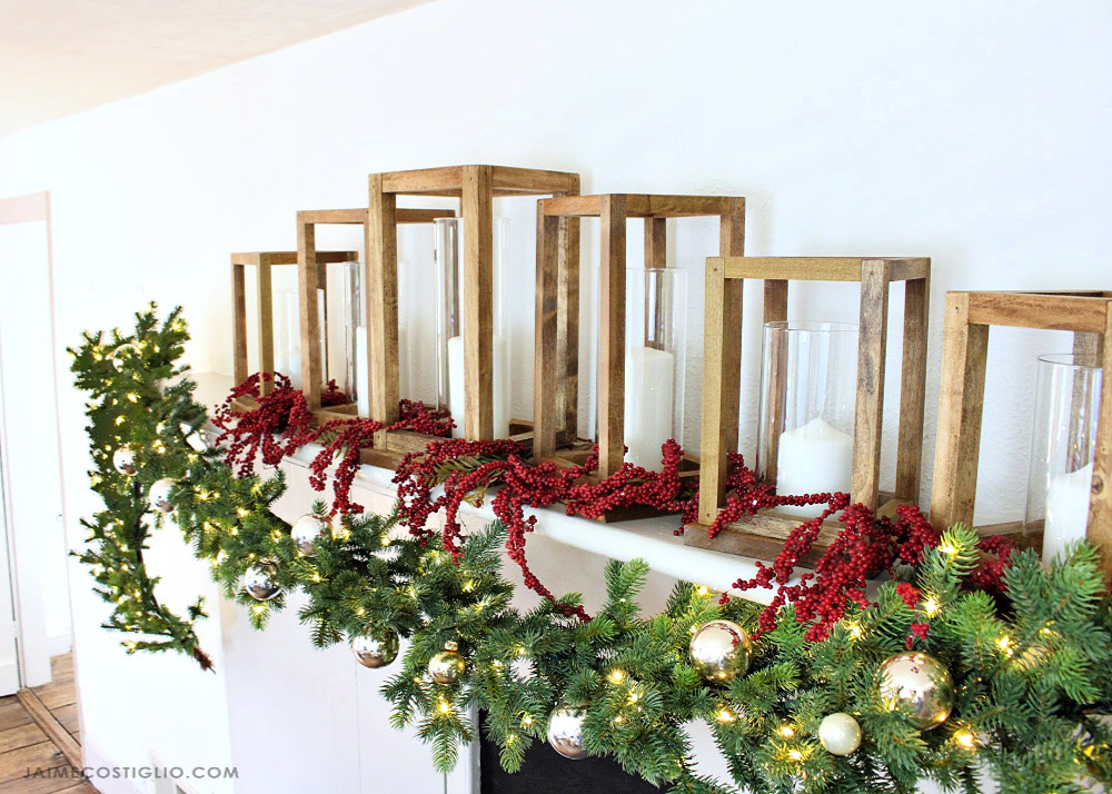 Holiday garland on a mantel with lights, ornaments and candles. 