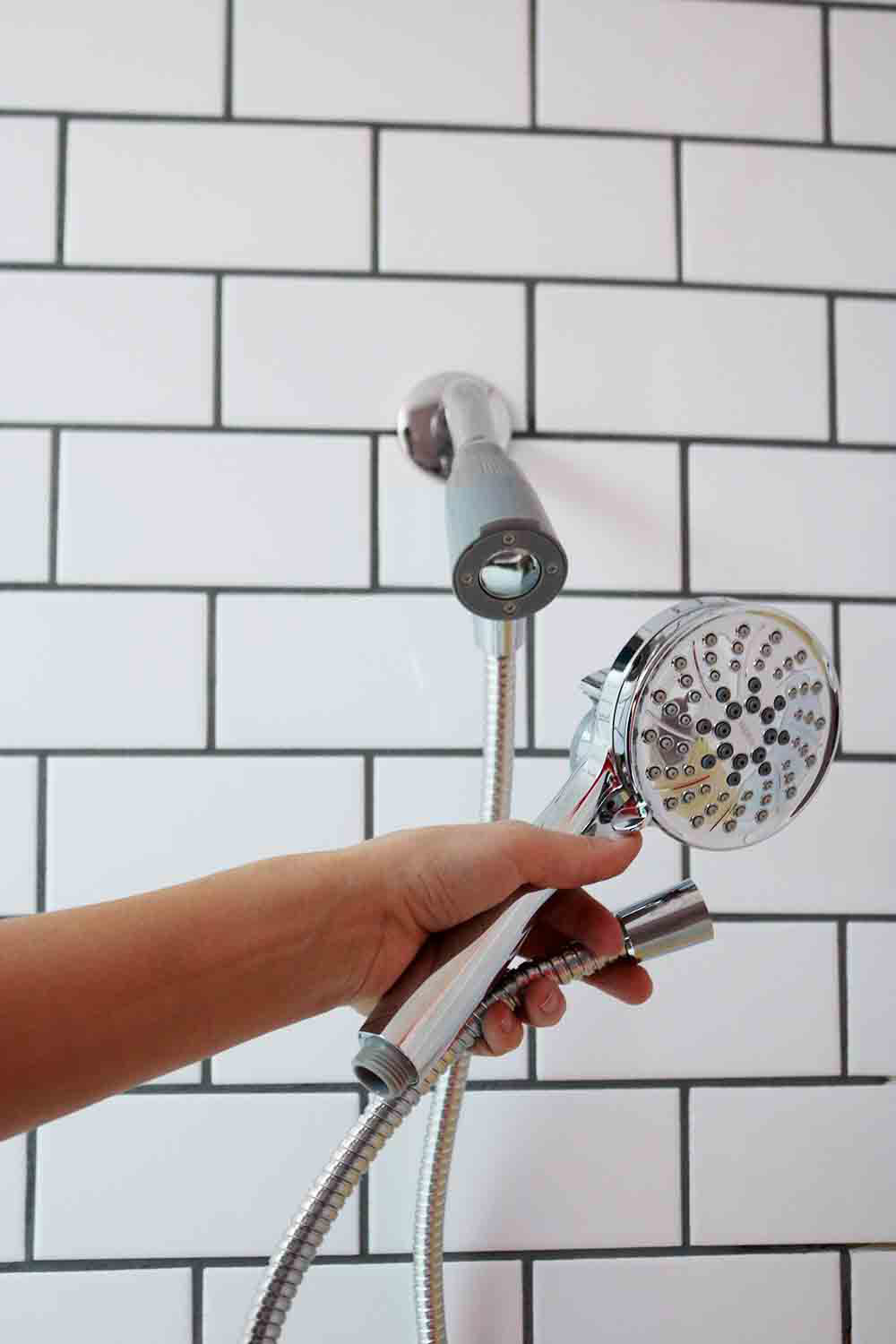 A person attaching a shower head onto a wall.