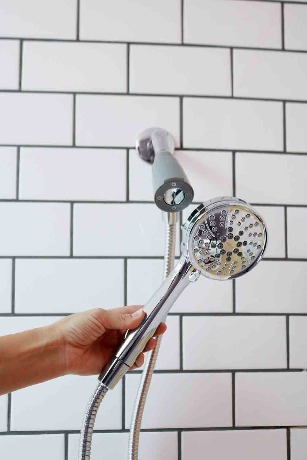 A person attaching a shower head onto a wall.
