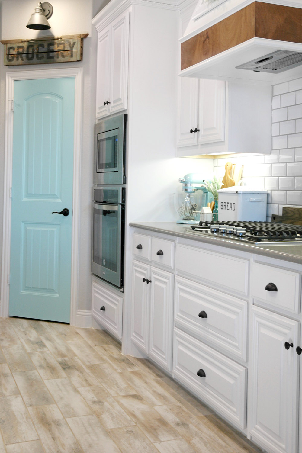 Kitchen with farmhouse theme, white cabinets and baby blue pantry door.