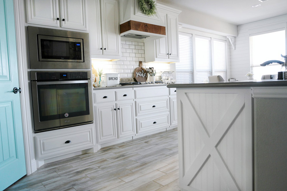 An open farmhouse style kitchen featuring white finishes and a kitchen island.
