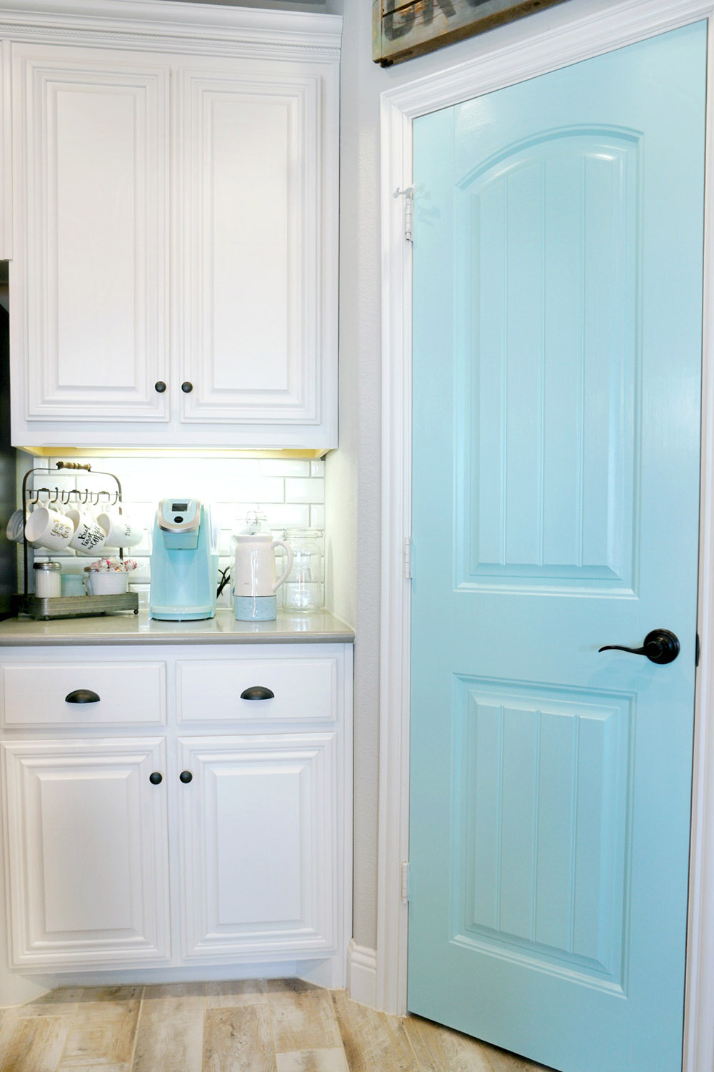 White kitchen cabinets and a baby blue pantry door.