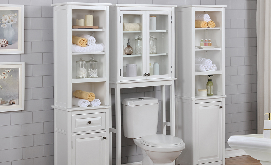 Toilet surrounded and topped with storage cabinets and open shelves.