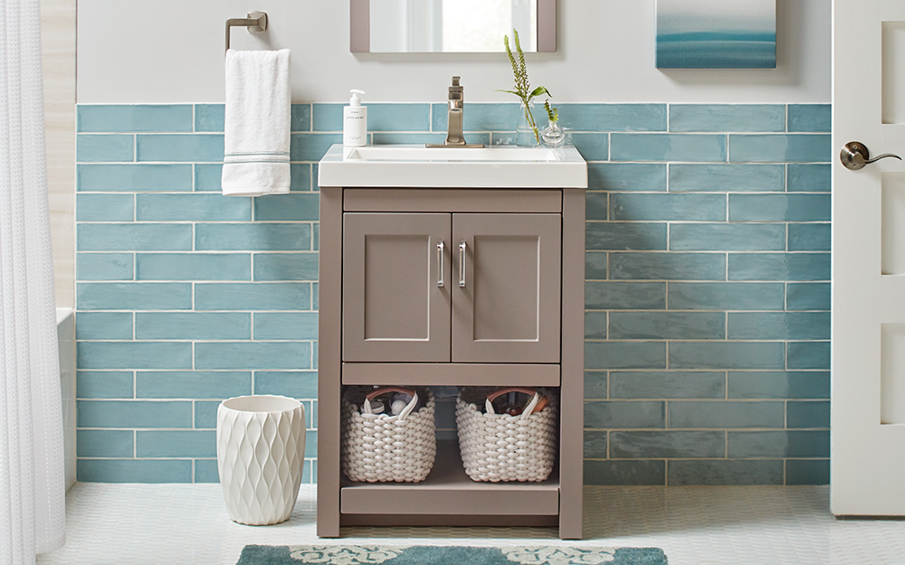 A gray single vanity installed in front of a blue tile wall.