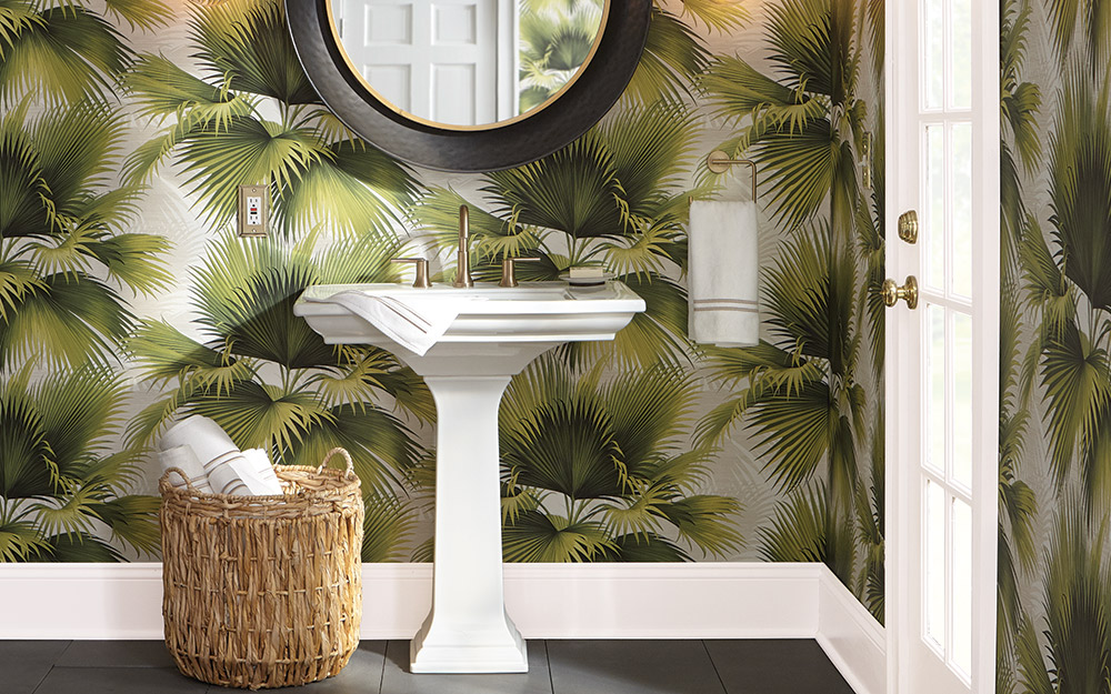 Wallpaper in a big tropical print behind a pedestal sink