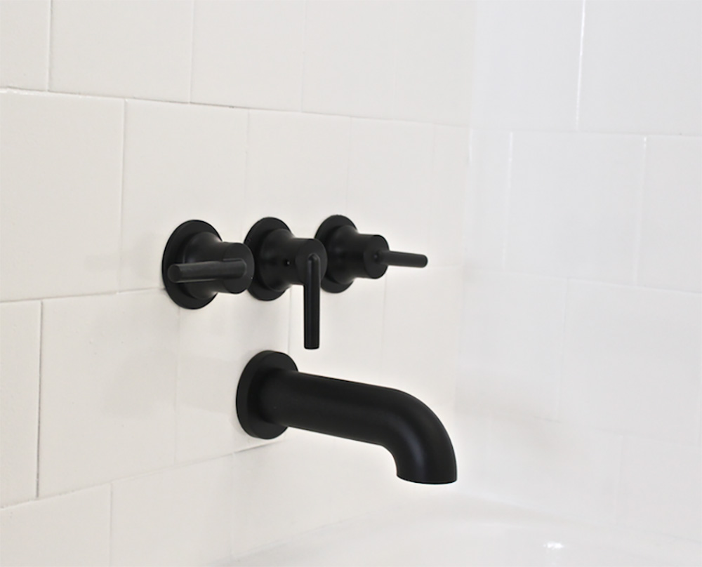 A white shower wall with black hardware.