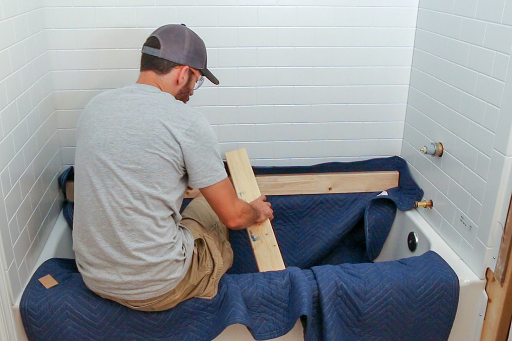 A person holding 2x4s in a tub. A person holding 2x4s in a tub.