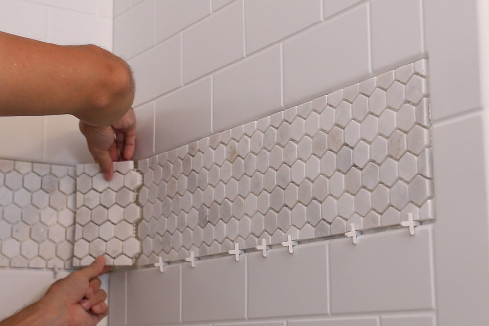 A person installing shower tile. A person installing shower tile.
