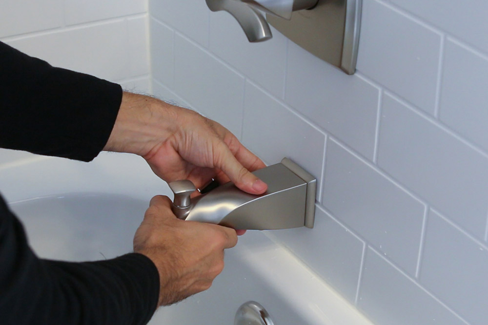 A person installing a bathtub faucet. A person installing a bathtub faucet.