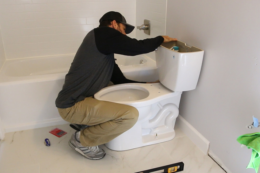 A person installing a toilet. A person installing a toilet.
