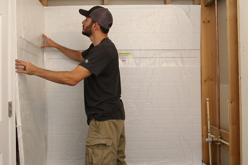 A person installing shower tile. A person installing shower tile.