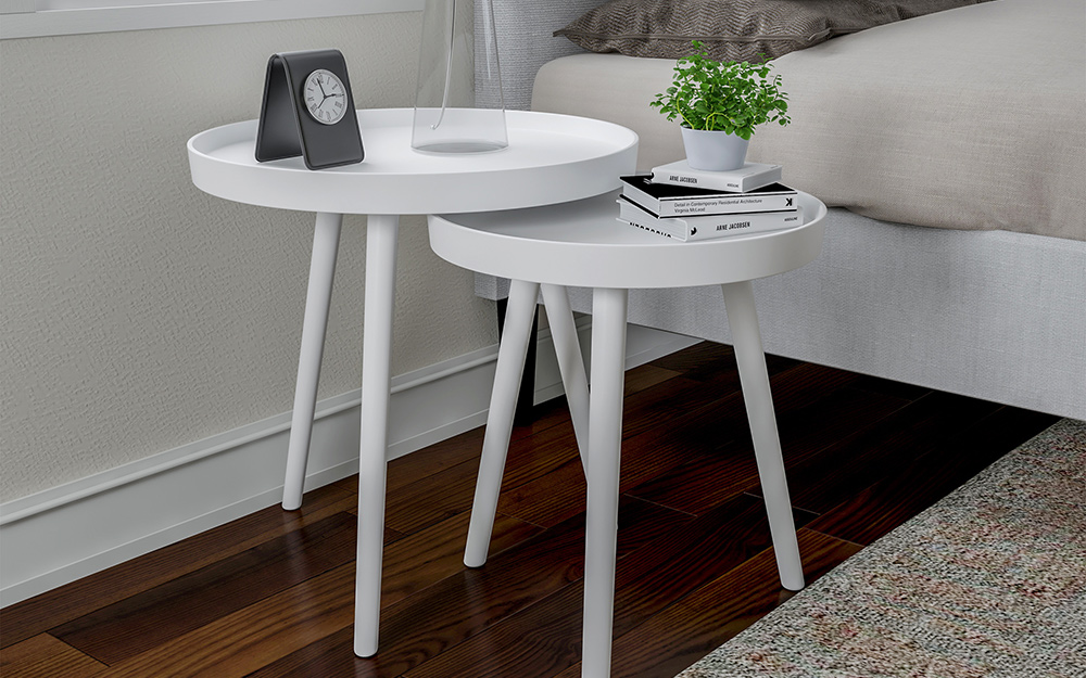 Two white nesting tables beside a bed Two white nesting tables beside a bed