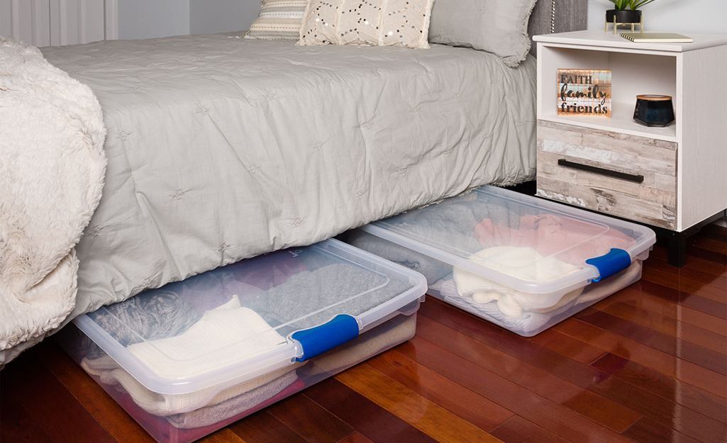 Under bed storage bins filled with folded winter clothes.