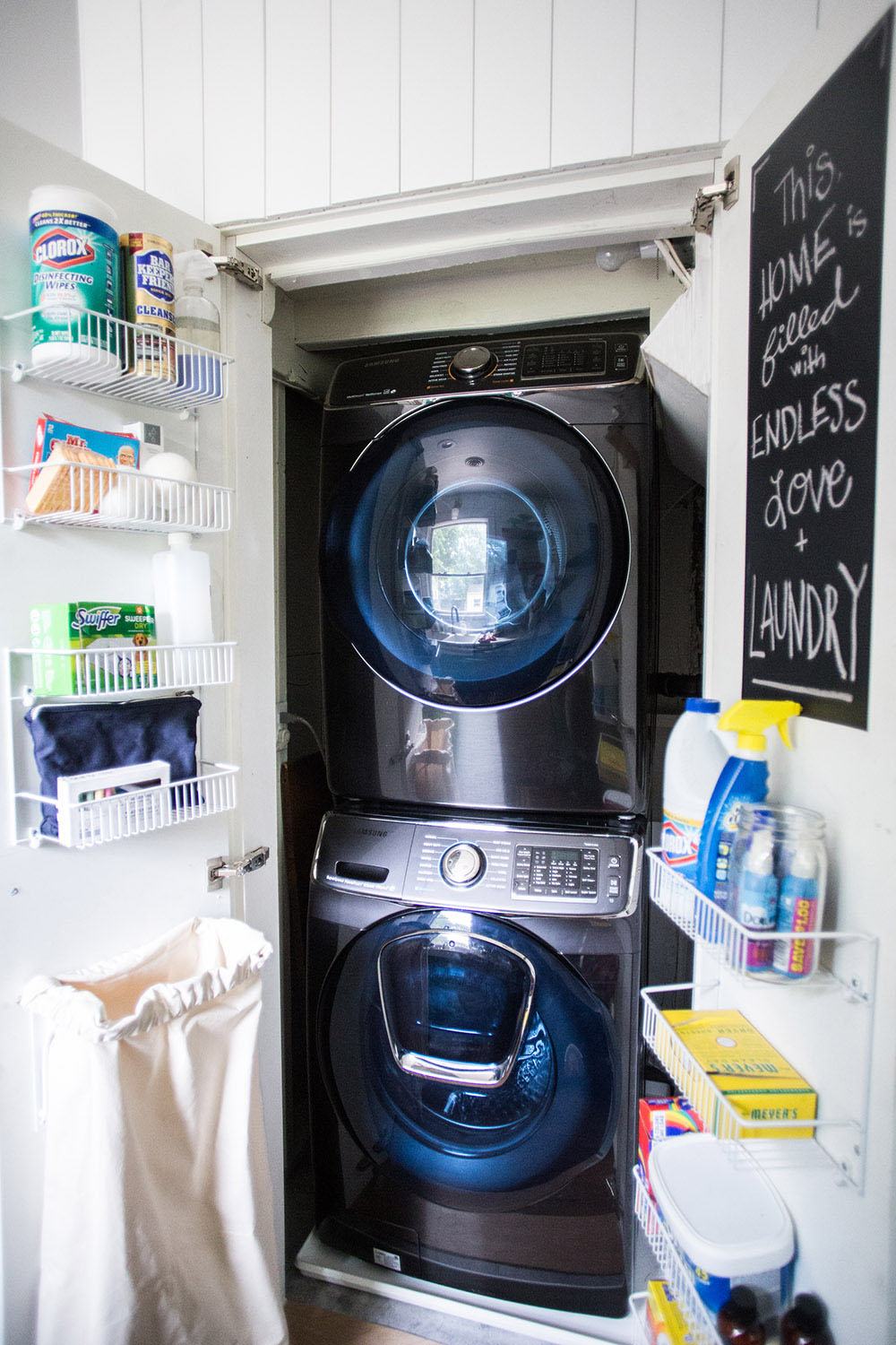 A closet with a washing machine, a dryer, and shelves on the doors.