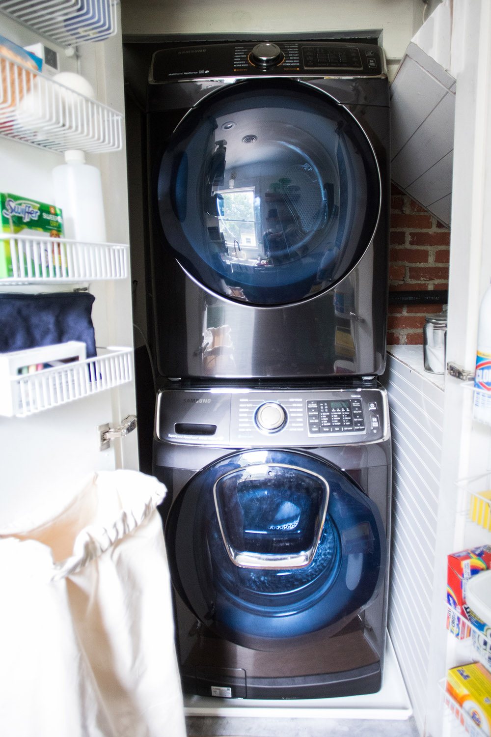 A closet with a washing machine, a dryer, and shelves on the doors.