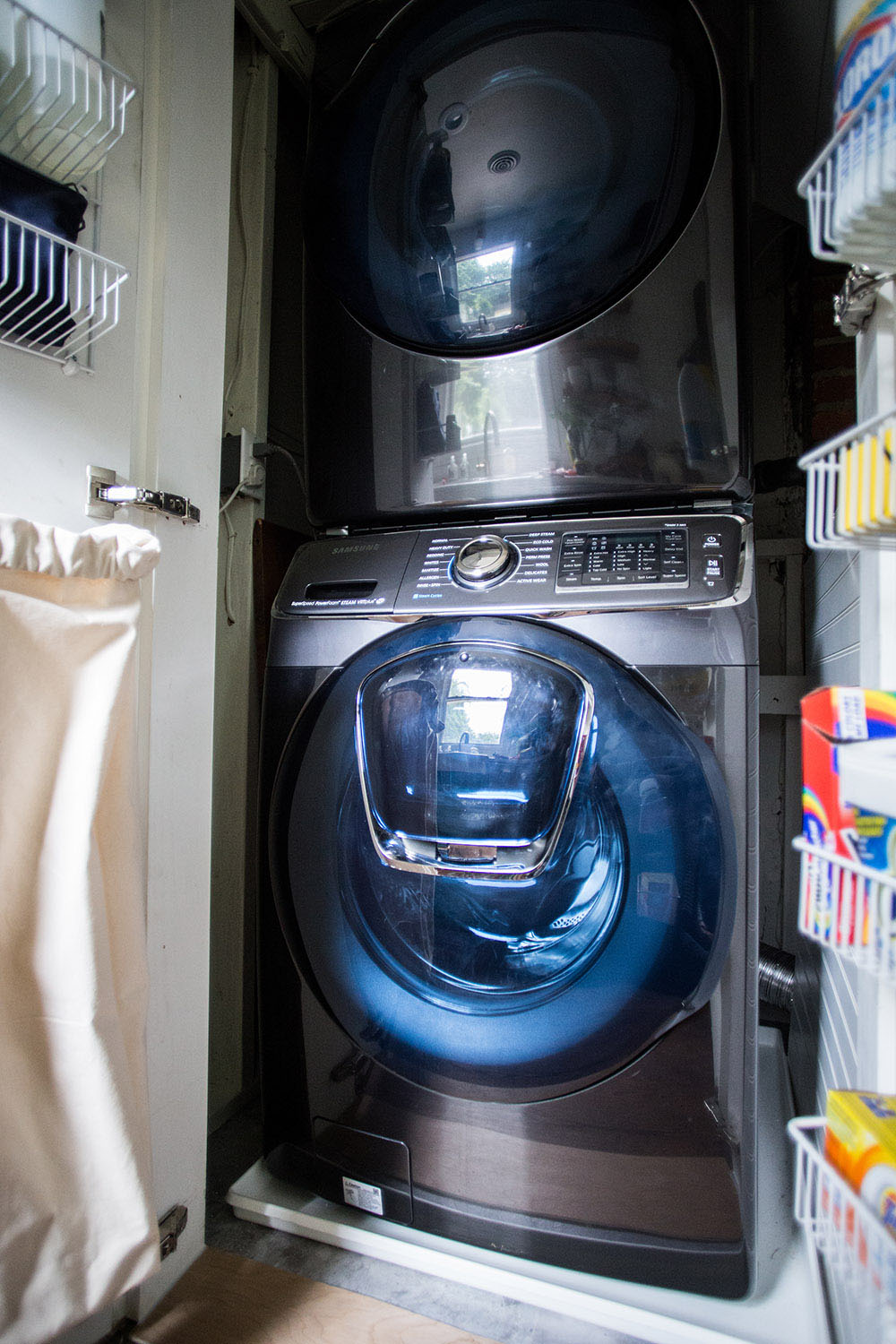 A closet with a washing machine, a dryer, and shelves on the doors.