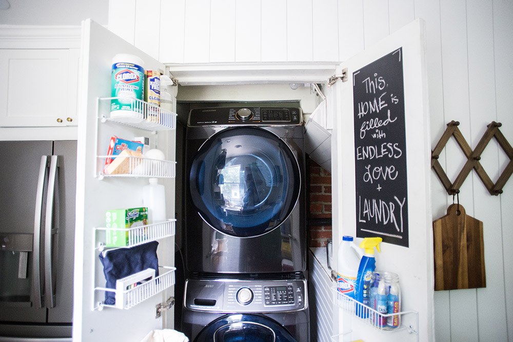 A closet with a washing machine, a dryer, and shelves on the doors.