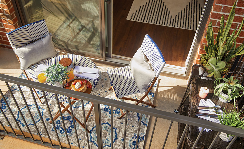 A breakfast laid out on a small round table on a balcony patio.