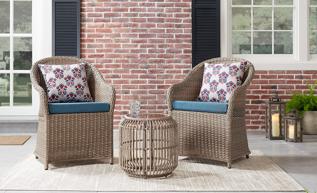 Two chairs and a matching table set up on a small patio.