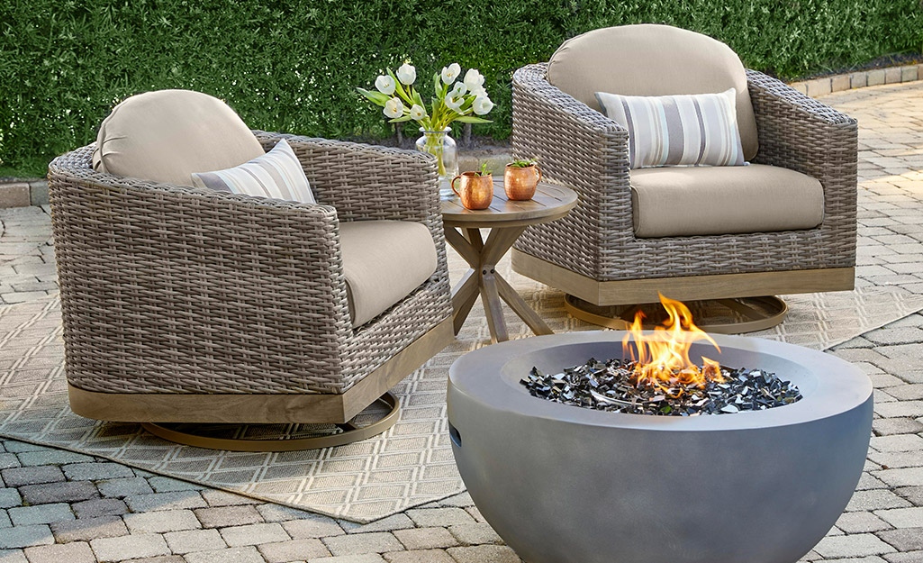 A brick patio featuring a fire pit and set of chairs.