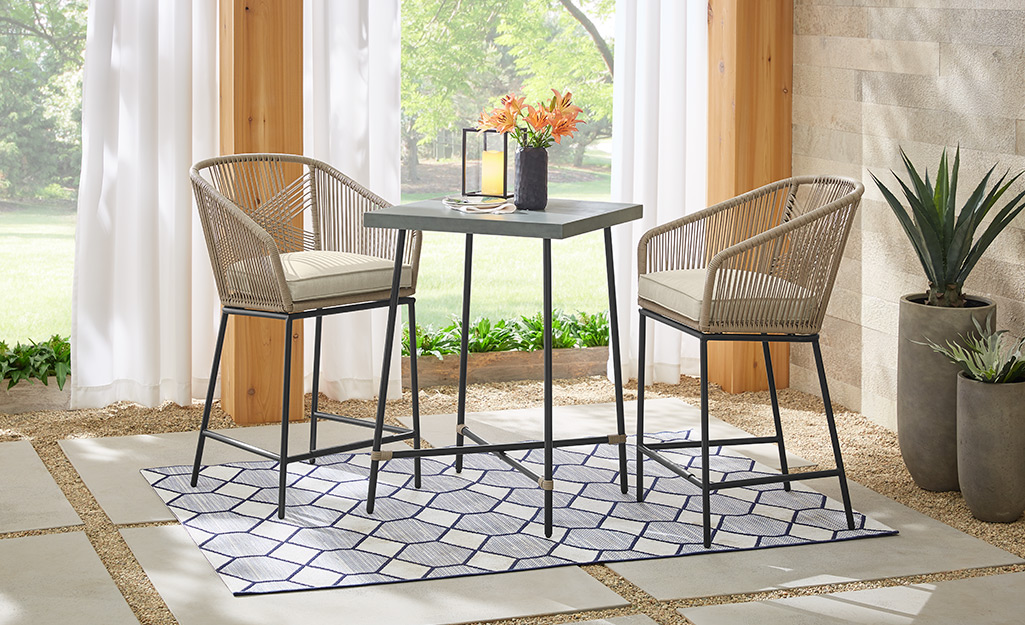 A bar-height table and chairs sitting on a small patio.