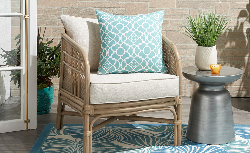 Throw pillows and outdoor patio accessories placed on and around a chair.