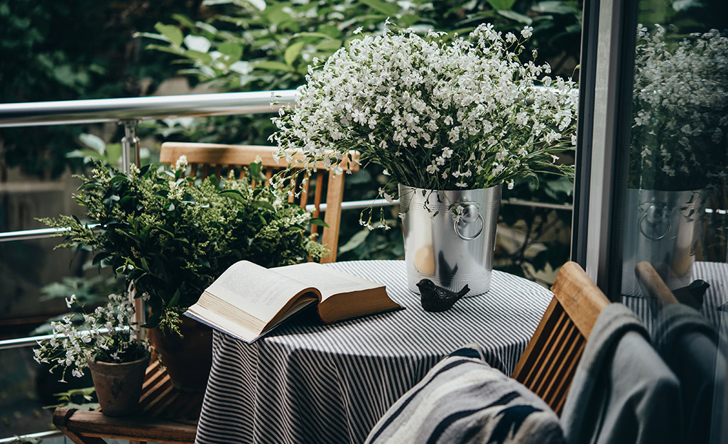 A book and a vase with flowers sitting on a small round table on a patio.