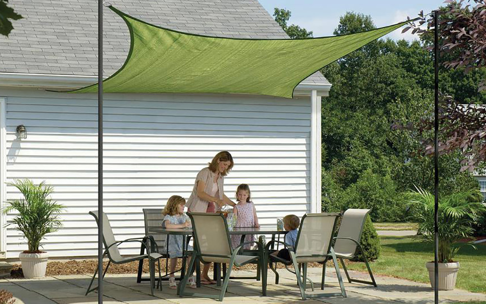 a family gathered around a patio dining set covered by a sun sail